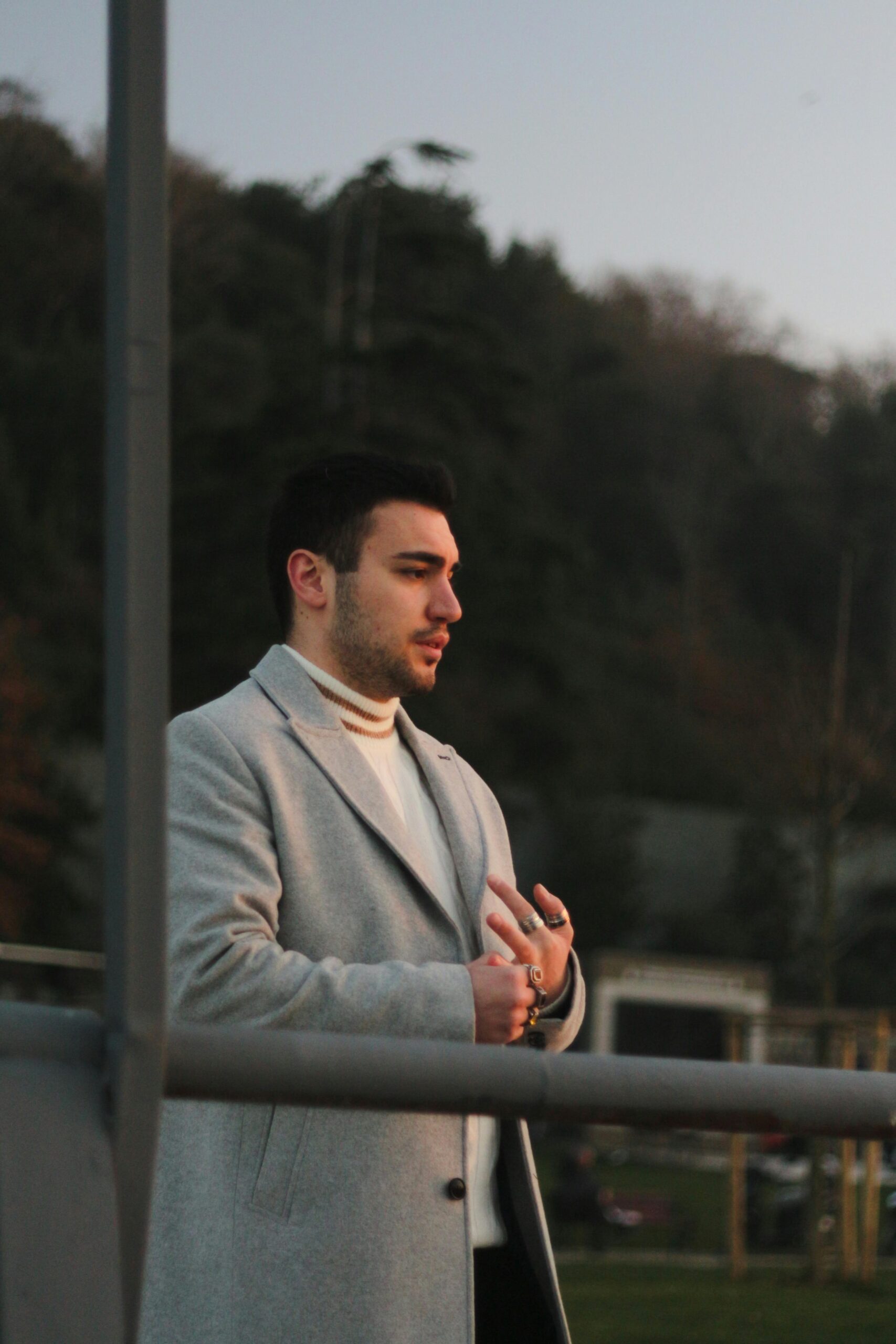 A man in a gray coat enjoying the scenic sunset in Istanbul, Türkiye.